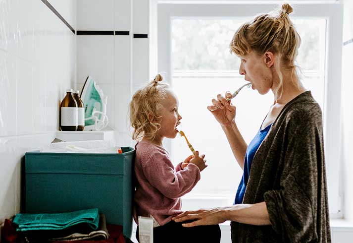 Mor og datter på badeværelset mens de børster tænder